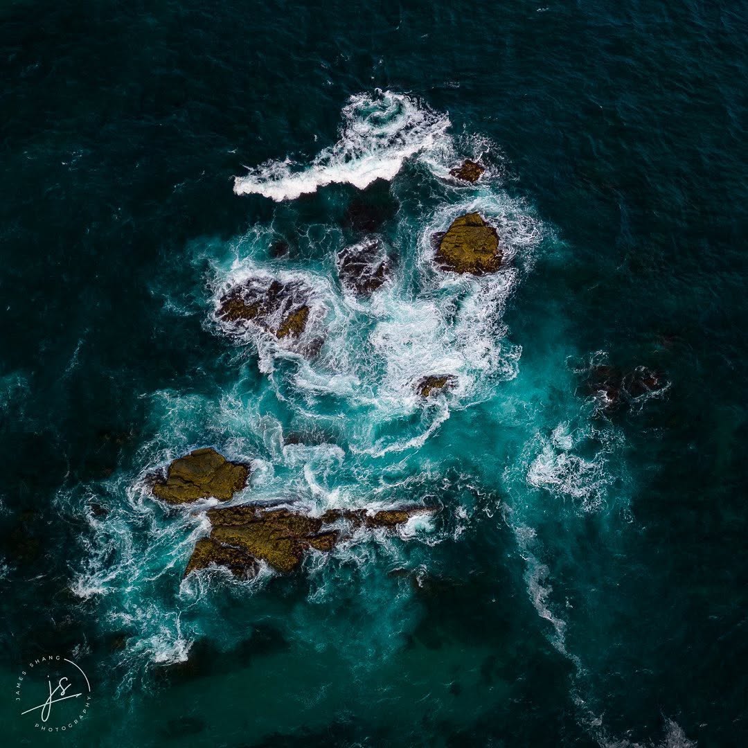 Aerial view of surf breaking over offshore rocks